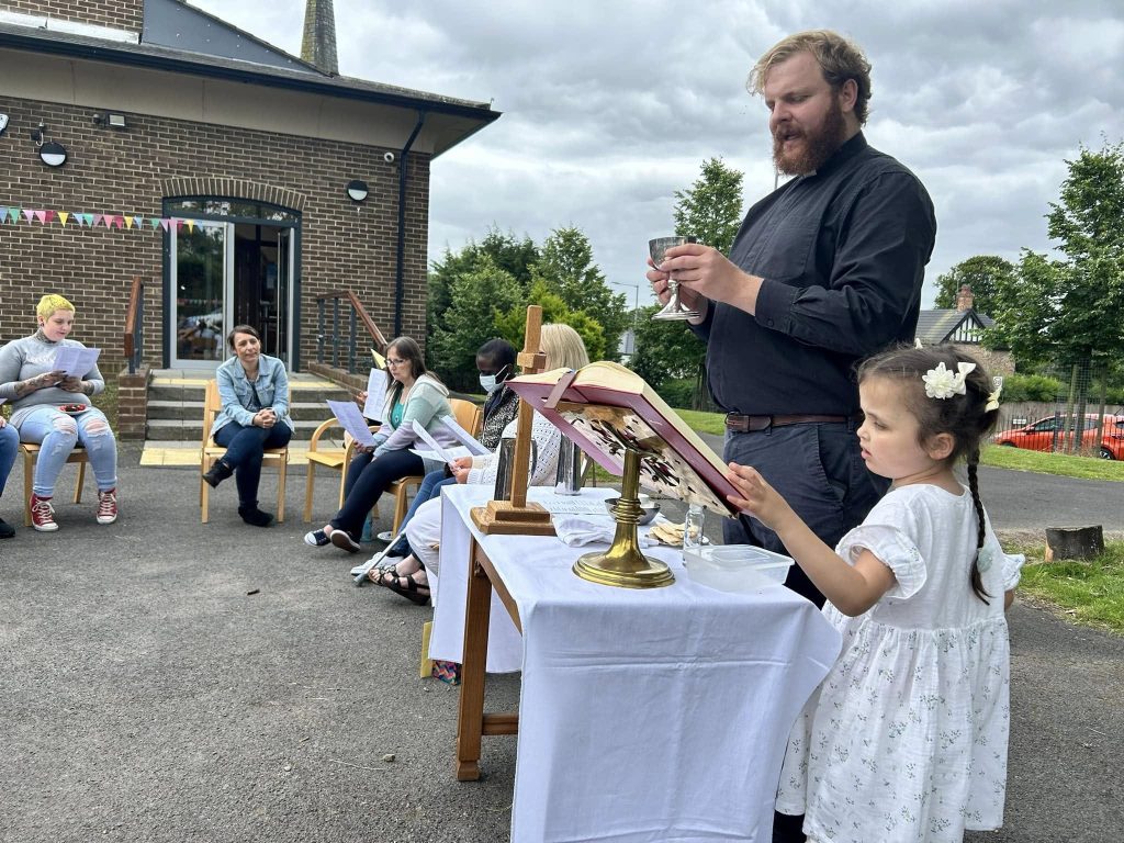 Rev Alfred leading communion outside
